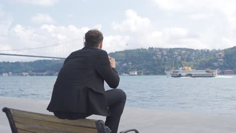 thoughtful businessman watching the ship passing through the strait.