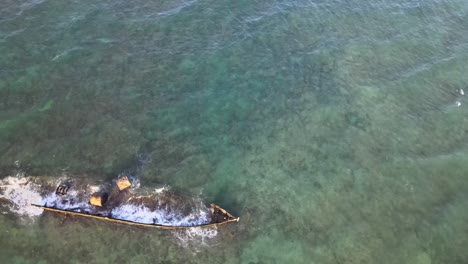 drone aerial over blue water and the historical mildura shipwreck with waves crashing over it