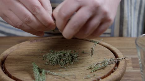 chef crushes fresh thyme with his hands for chimichurri, on wooden board