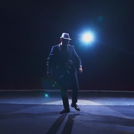 senior man in costume on stage in darkness. active man in hat dancing on stage during the performance in the theater.