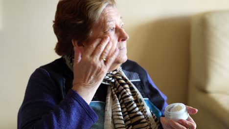 old woman applying anti-wrinkle cream to face