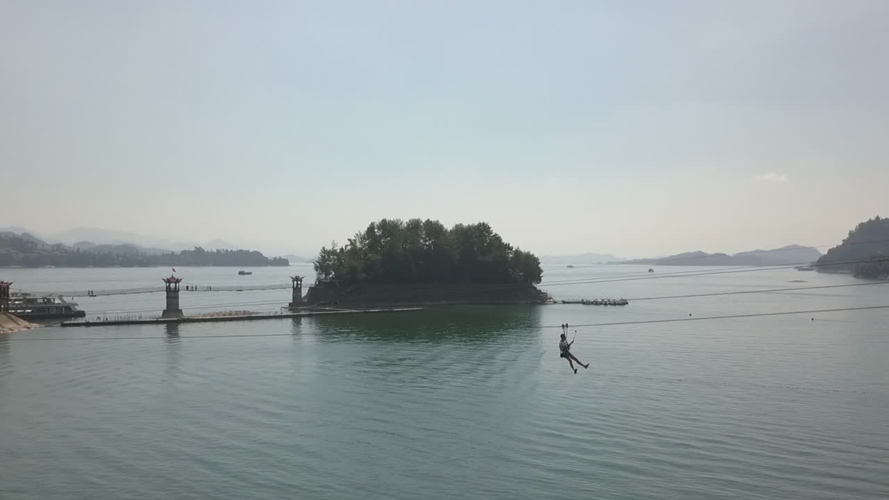 турист снимает себя с помощью палки для селфи на зиплайне над водой озера