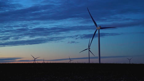 silhouette of wind power generators flashing red on a dramatic, vibrant evening