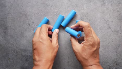 hands holding and inspecting blue lithium-ion batteries