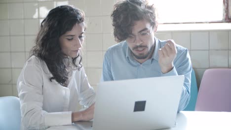 thoughtful young man talking with confident colleague