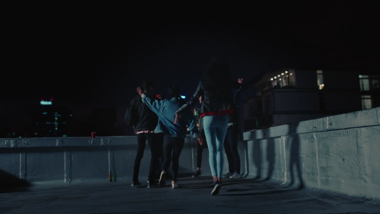 grupo feliz de amigos bailando a la música animada de la fiesta en la azotea disfrutando de la celebración del fin de semana en la ciudad urbana por la noche