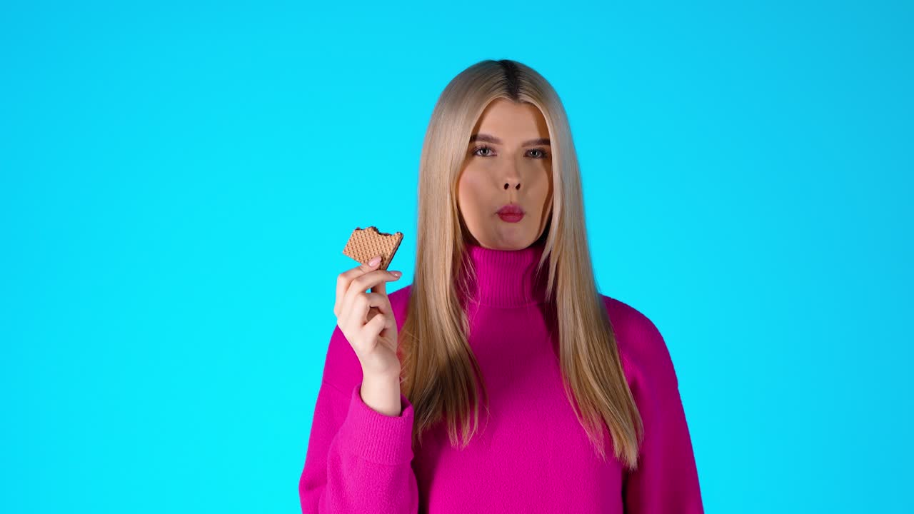 Young Attractive Blonde Woman Eating Wafer, Colorful Studio Portrait