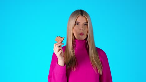 young attractive blonde woman eating wafer, colorful studio portrait