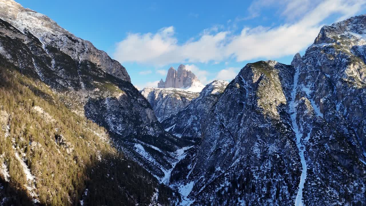 Breathtaking valley in the Italian Dolomites with The Drei zinnen in the background during winter season (drone footage)