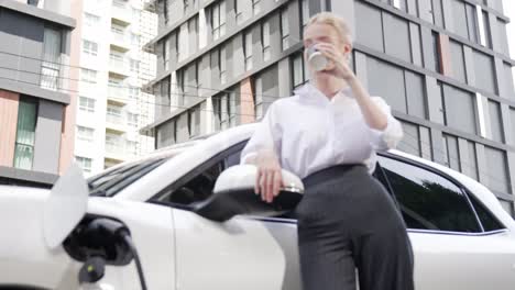 Progressive-businesswoman-leaning-on-electric-car-and-charging-station.