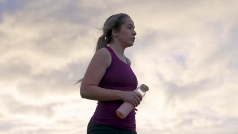 Mujer-De-Pie-En-La-Colina-Después-Del-Entrenamiento-Contrasta-El-Cielo-Del-Amanecer-Detrás