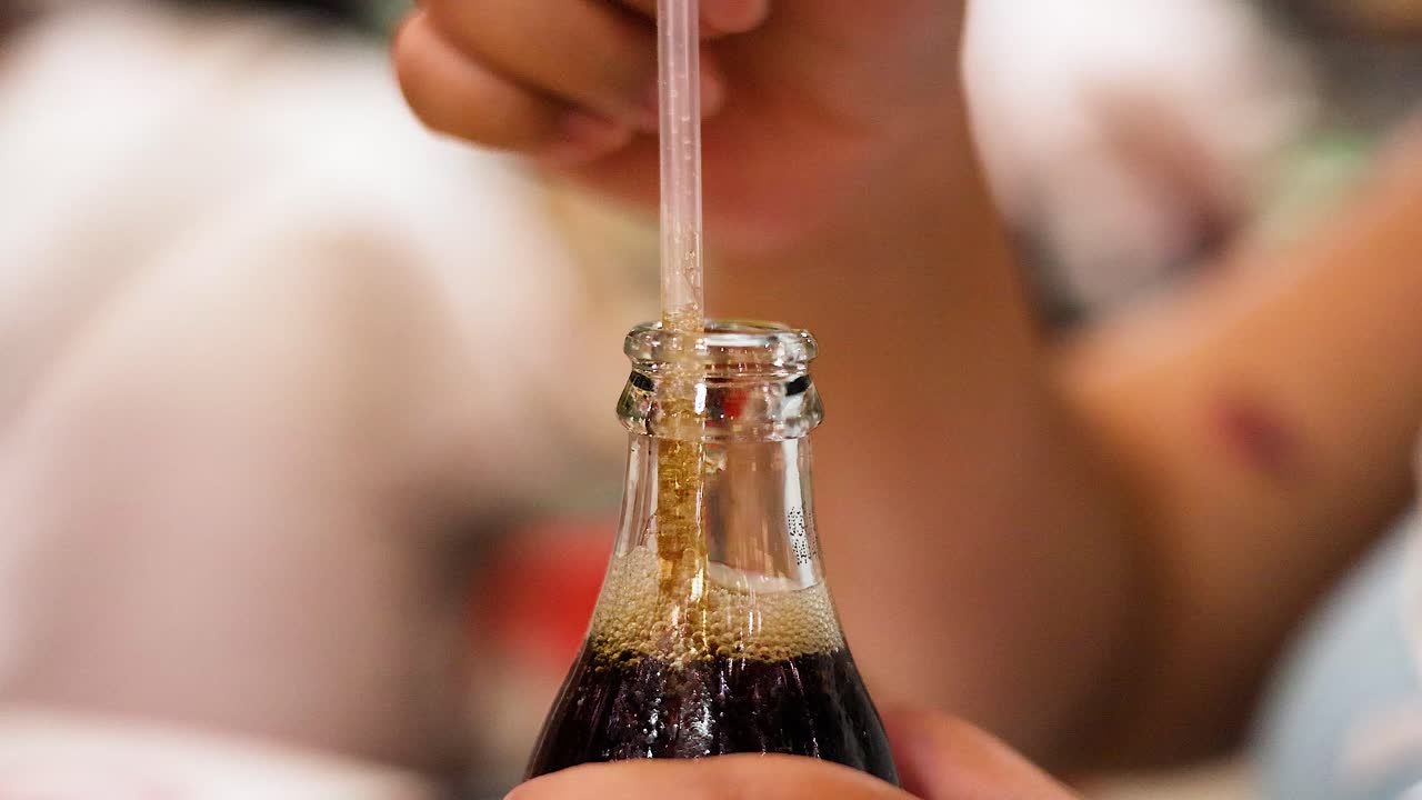 colocación manual de paja en la botella de refresco