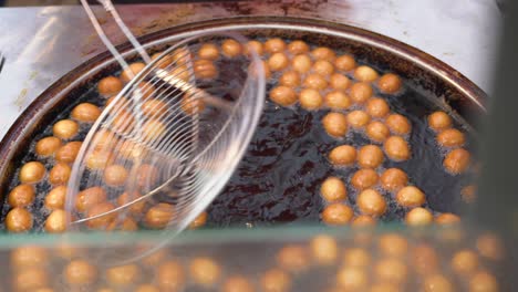 rosquillas hirviendo en aceite caliente en la feria de la ciudad. primer plano de pasteles dulces fritos en aceite