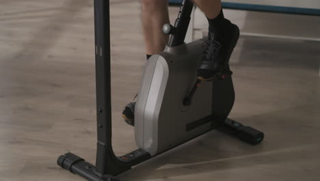 male feet are spinning pedals during training on stationary bike closeup shot healthy lifestyle and fitness at home or gym