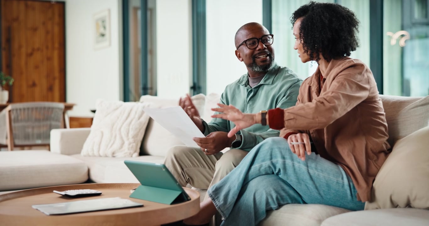 Mature Couple Reviewing Financial Documents Together on Sofa