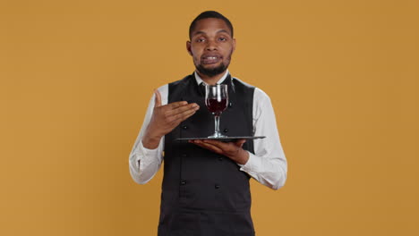 camarero sirviendo a los clientes con un vaso de vino tinto antes de la cena