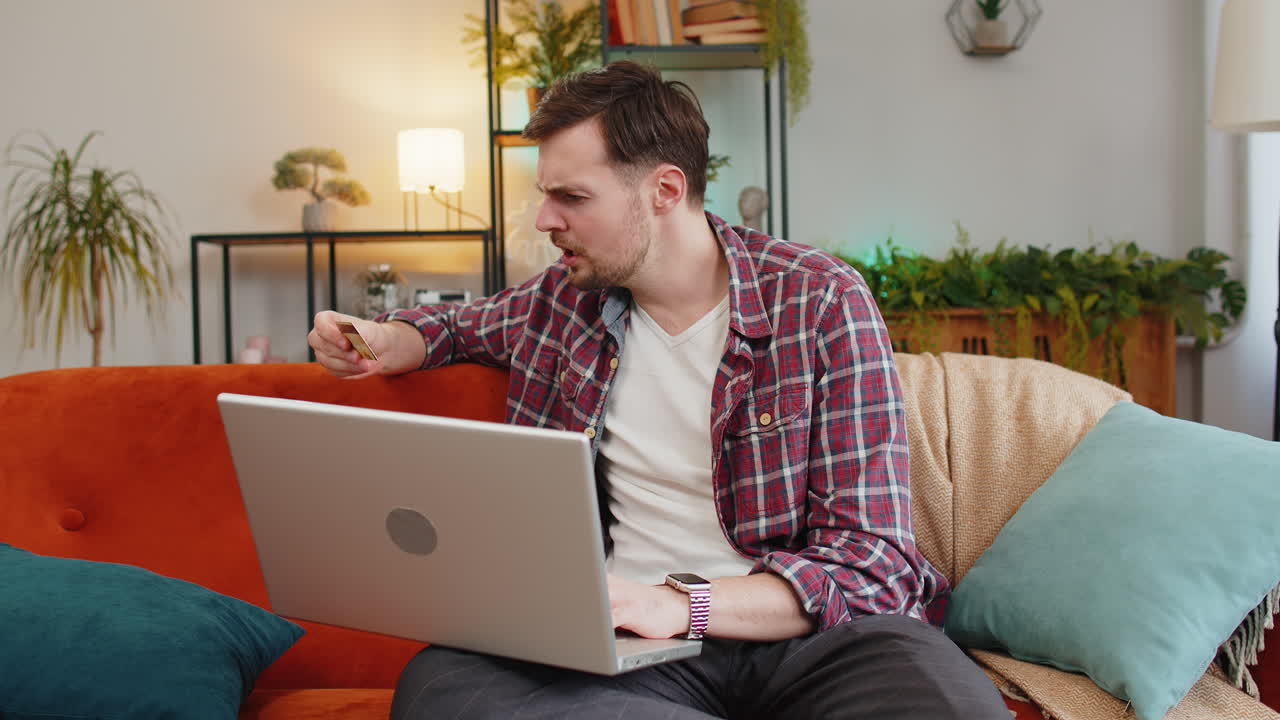 hombre usa portátil y tarjeta de crédito tratando de hacer pago a través de internet se siente enojado debido a la falta de dinero