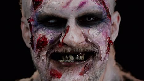 Zombie-man-face-makeup-with-wounds-scars-and-white-contact-lenses-looking-at-camera,-trying-to-scare