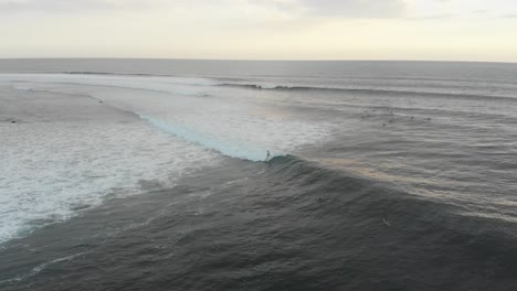 aerial view of people surfing at bali indonesia at sunset, drone