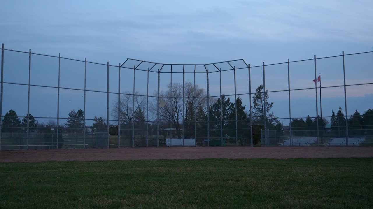 여름 저녁에 야구 다이아몬드와 백스톱 울타리, 잠김