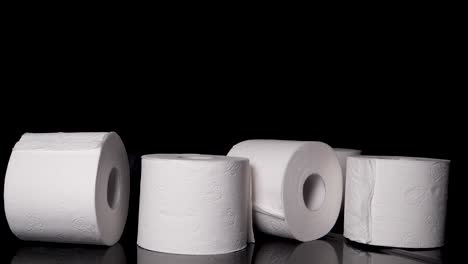 rolls of toilet paper falling in abundance, black background slow motion