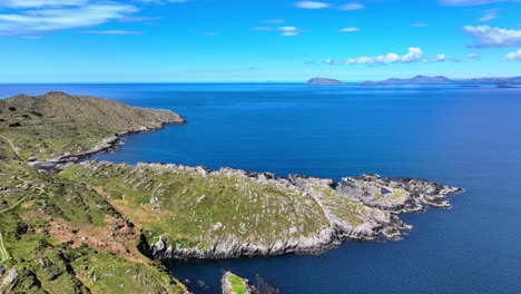 Paisaje-De-Drones-Promontorio-Rocoso-Mar-Azul-Tranquilo-Y-La-Costa-Del-Anillo-De-Kerry-En-El-Fondo,-Camino-Atlántico-Salvaje-De-Irlanda