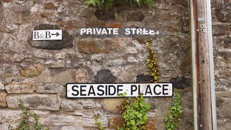 street signs on a stone wall in aberdour