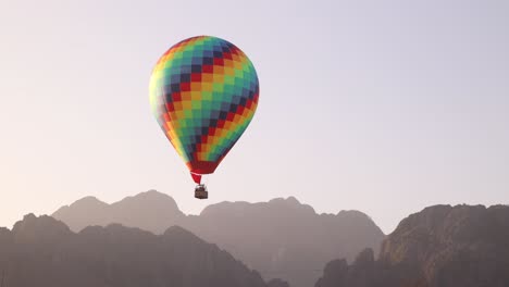 colorful hot air ballon floating over mountains in vang vieng, the adventure capital of laos