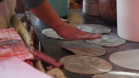 una mujer volviendo tortillas en una placa caliente en un puesto en méxico