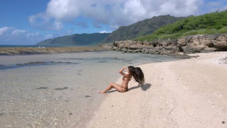 el paisaje de la playa está elevado por una belleza besada por el sol con largo cabello negro y un impresionante bikini marrón