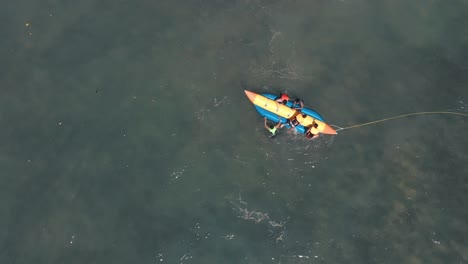 aerial birds eye spinning shot of people trying to climb banana boat