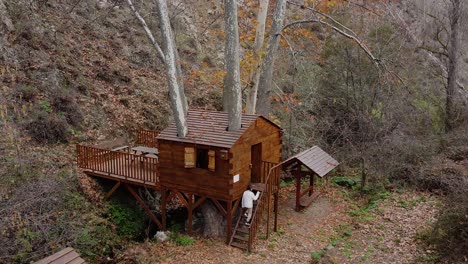 Wide-shot-of-a-little-girl-entering-a-wood-cabin-in-the-forest