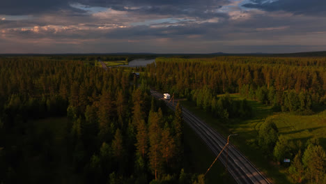 aerial view following a rv driving in middle of sunlit forests of lapland