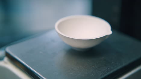 man-puts-chain-into-bowl-on-scale-in-jewelry-shop-closeup