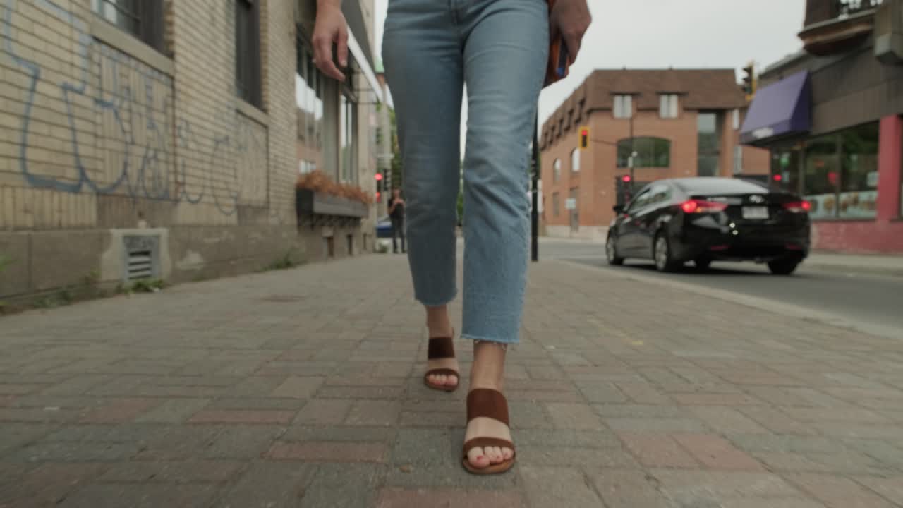 Camera moving around a woman wearing jeans and sandals walking in the city