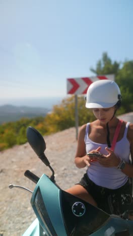mujer en un scooter tomando una foto en una montaña