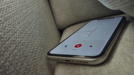 voice detection and recording app in mobile phone listening to contestation laying on couch or sofa hidden from view. secretly grabbing and wiretapping inside home or apartment during covert operation