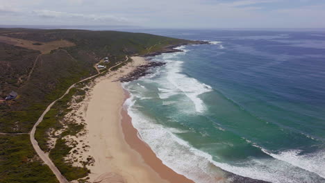 Sudáfrica-Quieto-Bahía-Playa-Vacía-Aéreo-Dron-Cinemático-Playa-Pequeño-Surf-Pueblo-Jardín-Ruta-Jeffreys-Bay-Olas-Rompiendo-Agua-Azul-Verde-Océano-A-última-Hora-De-La-Mañana-Tarde-Movimiento-Hacia-Abajo