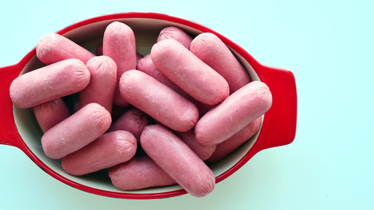 salchichas rosadas crudas en un cuenco rojo