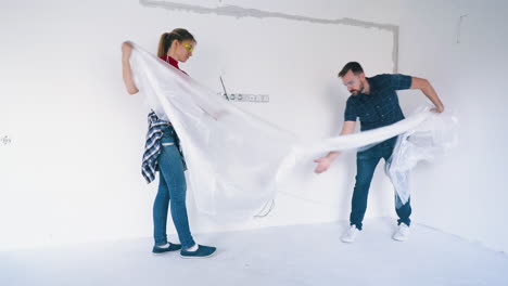 woman and bearded man shake foils near white wall in room