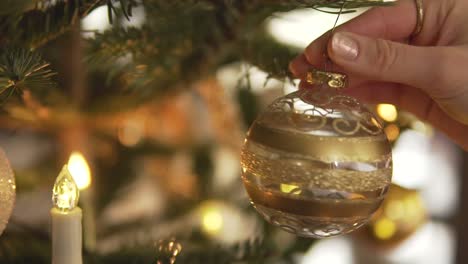 Slow-Motion:-Hanging-golden-Christmas-bauble-on-decorated-tree,-close-up