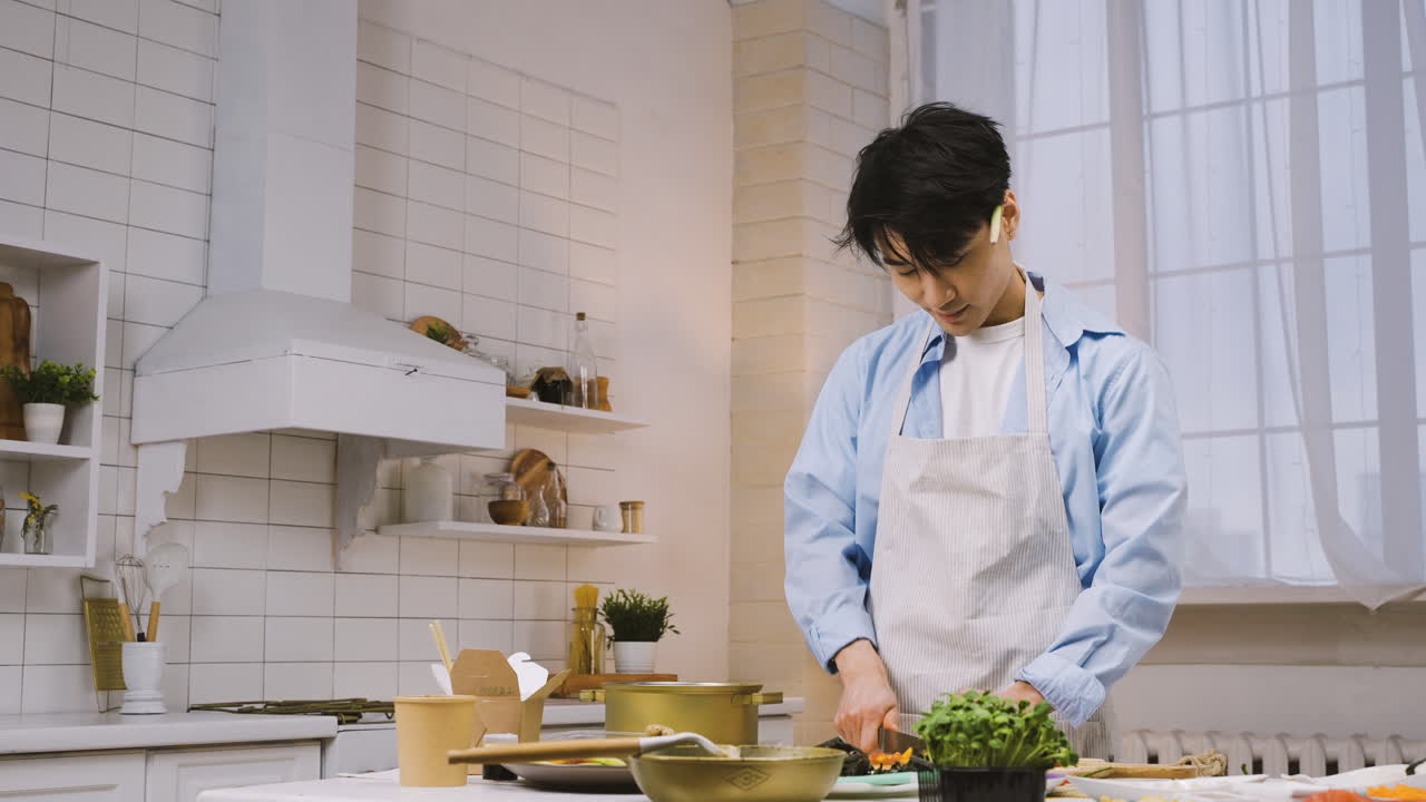 hombre japonés cortando ingredientes en la cocina, luego mira a la cámara y sonríe 3