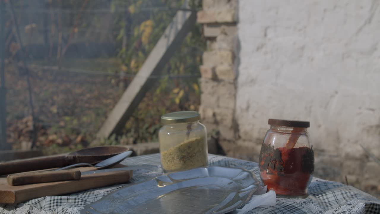 баночки с натуральными специями на столе рядом с дымящимся грилем на открытом воздухе