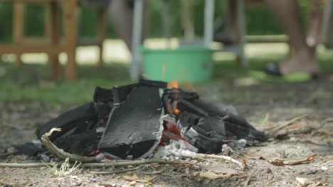 Pequeña-Hoguera-Ardiendo-En-El-Suelo-Haciendo-Carbón-Para-Fuego-O-Barbacoa-Al-Aire-Libre-Durante-El-Día-Caluroso