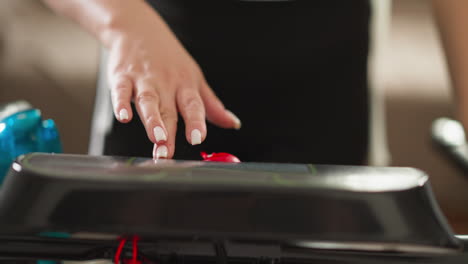 woman's hand pressing red button on treadmill