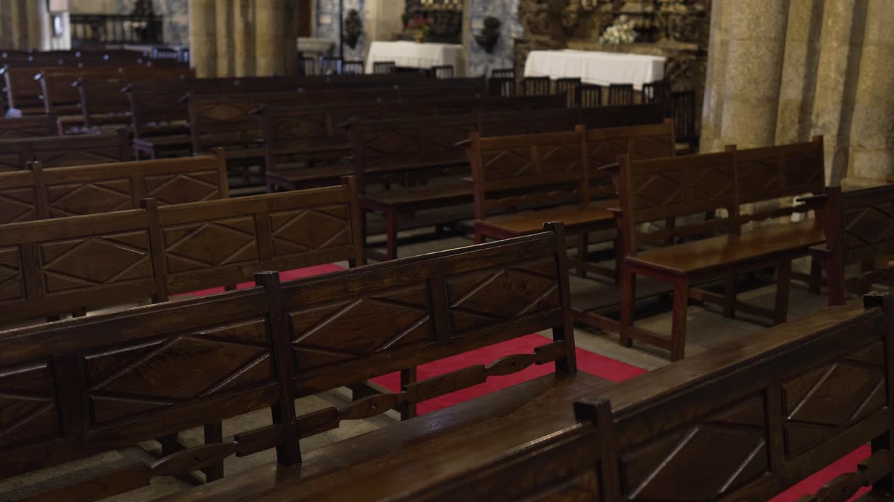 Wooden pews with red carpet inside old stone church prepared for ceremony