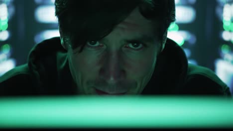 an intense gaze: a focused individual working with technology in a dimly lit environment, surrounded by glowing screens and data visualizations