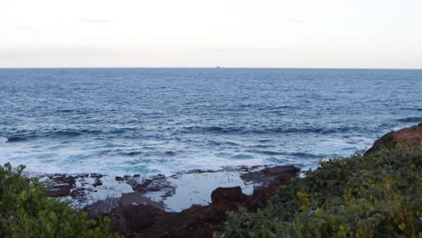 Beautiful-vast-ocean-view-with-rocky-coastline-and-distant-ship