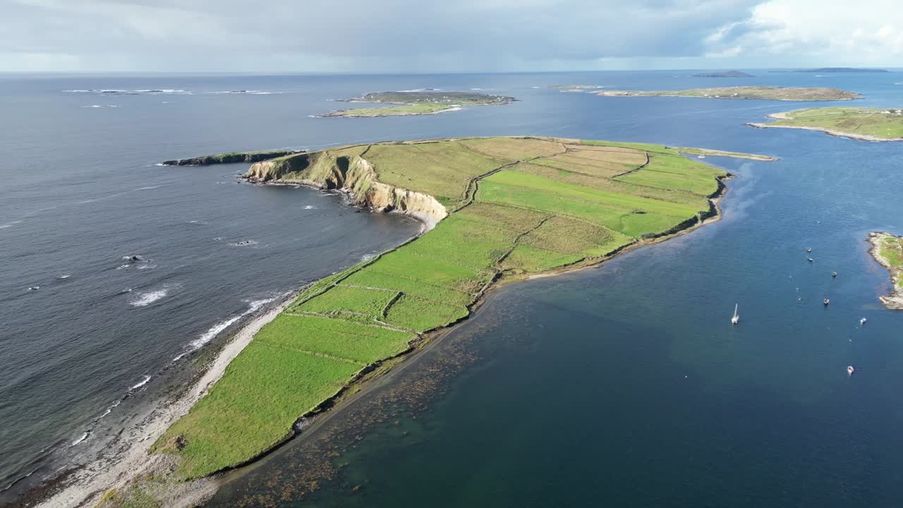 Aerial reveal over a rugged Connemara peninsula and coastal inlet in Galway, Ireland—showcasing yachts, rolling green fields, cottages and Atlantic cliffs in sweeping Irish rural life