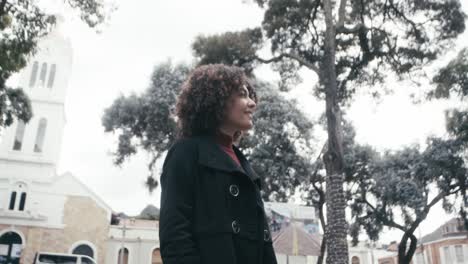 Low-angle-shot-of-woman-in-a-suit-with-curly-hair-walks-looking-around-in-the-city-of-Bogota,-Colombia